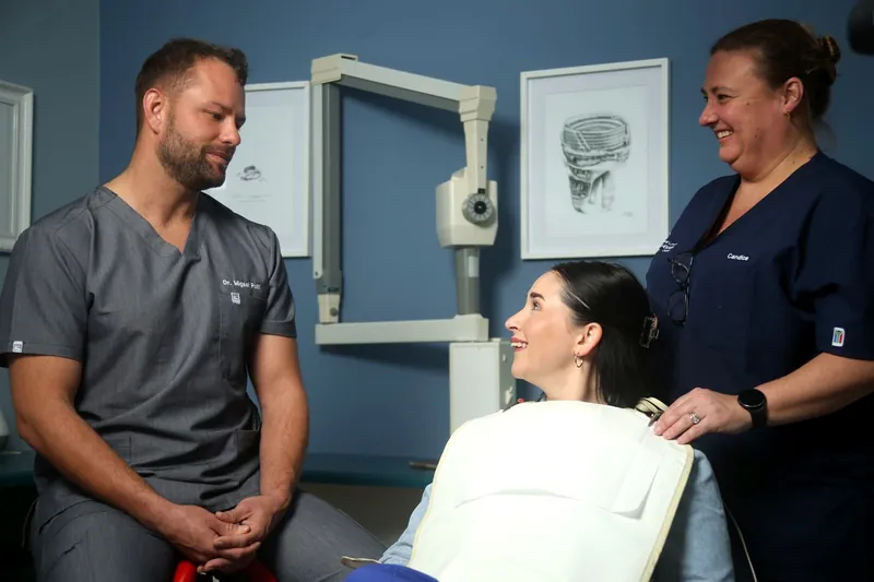 Dr Migael Pohl in consultation with a patient and a clinical assistant at East London Oral Health Centre